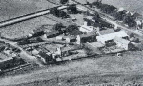 A black and white aerial photograph of a farmstead and surrounding fields.